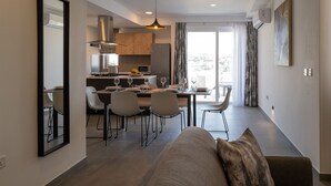 A modern living room with a sofa and a dining area with a table and chairs. - Portside Lodge Building (Marsaskala)