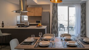 A modern kitchen with a dining area set for a meal. - Portside Lodge Building (Marsaskala)