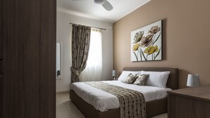 Un dormitorio con cama, cortinas, una obra de arte en la pared y lámparas de noche.