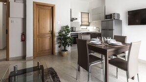 Una cocina moderna con zona de comedor, puerta de madera, planta en maceta y televisor de pantalla plana montado en la pared.