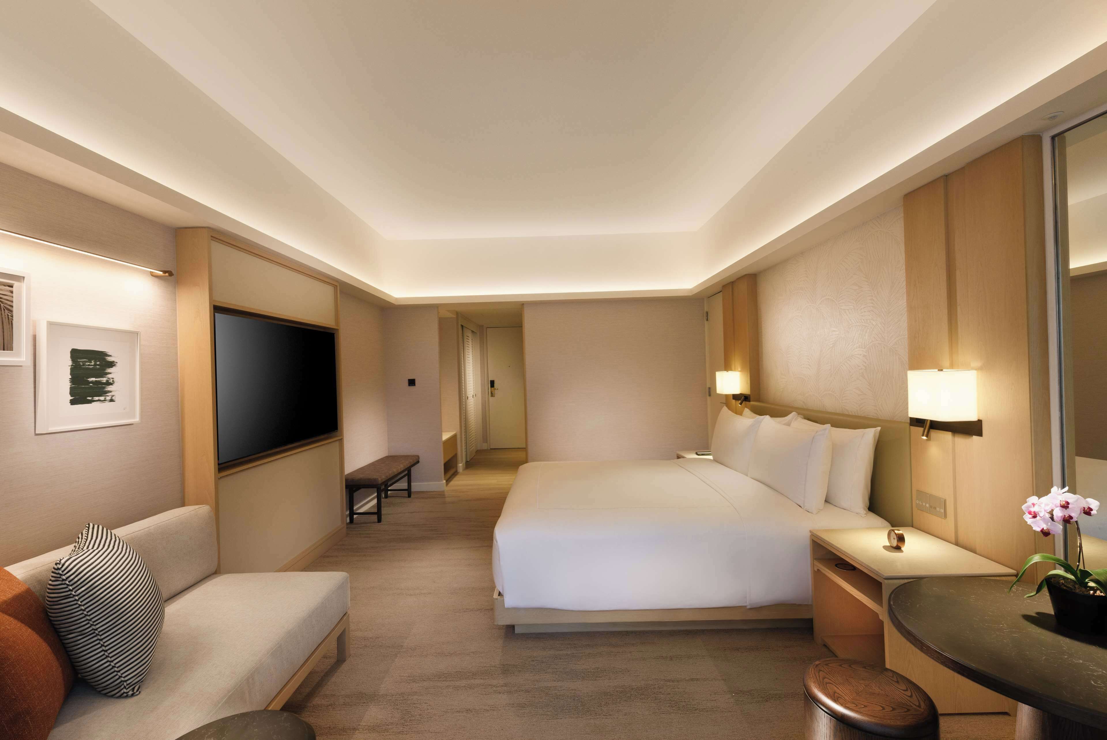 Quarto de hotel com uma cama grande, um sofá, uma escrivaninha e uma televisão de tela plana.