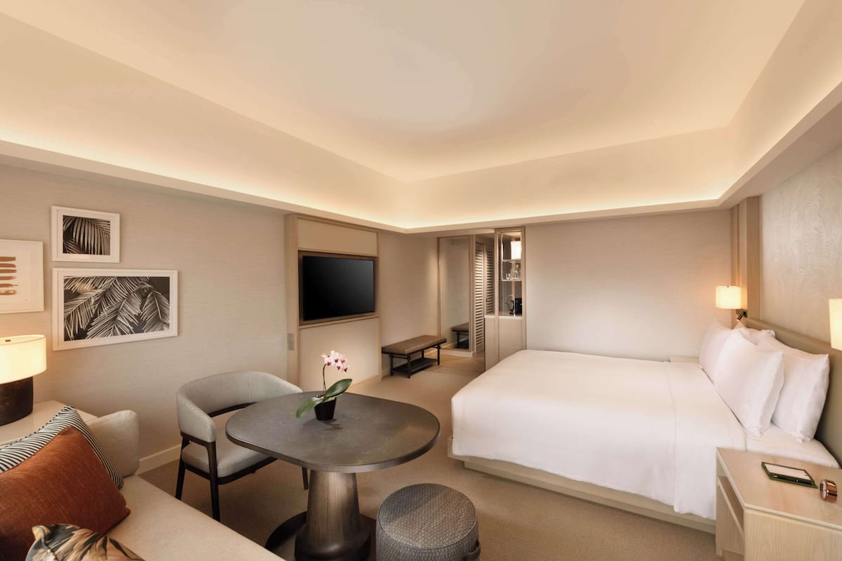 Een hotelkamer met een bed, een bureau, een stoel, een televisie en kunstwerken aan de muur.