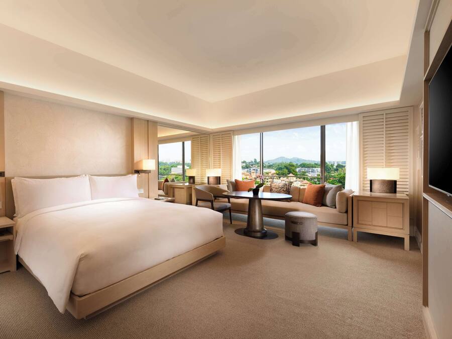 A hotel room with a large bed, a seating area with a table, and a TV.