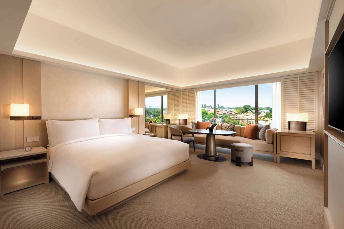 Een moderne hotelkamer met een groot bed, een zithoek met een tafel en een televisie.