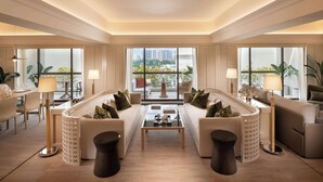 Een ruime woonkamer met twee banken, een salontafel en vloerlampen. Grote ramen bieden uitzicht op de skyline van de stad.