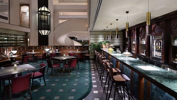 A modern hotel lobby with a bar area, seating arrangements, and a staircase.