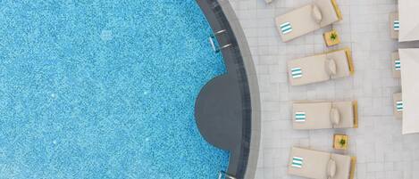 Una piscina circular con sillones y tumbonas alrededor.