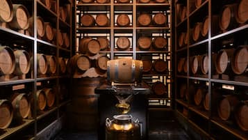 Un sótano de vinos con barriles de madera y una gran bomba de vino.