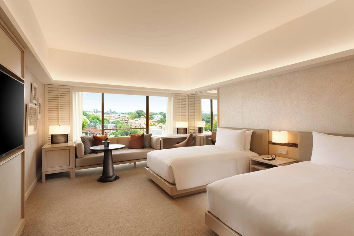 Een hotelkamer met twee bedden, een bank, een kleintje tafeltje en een televisie.