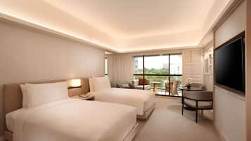 Habitación de hotel con dos camas, un escritorio y televisión.