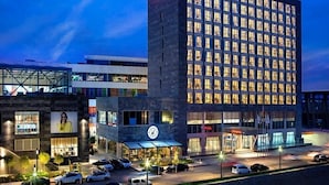 A modern hotel with a prominent Hampton sign, a glass facade, and a parking lot. - Hampton By Hilton Kocaeli Symbol (Basiskele)