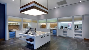 A modern kitchen with white cabinetry, a central island with a sink, and various kitchen appliances. - Hampton By Hilton Kocaeli Symbol (Basiskele)