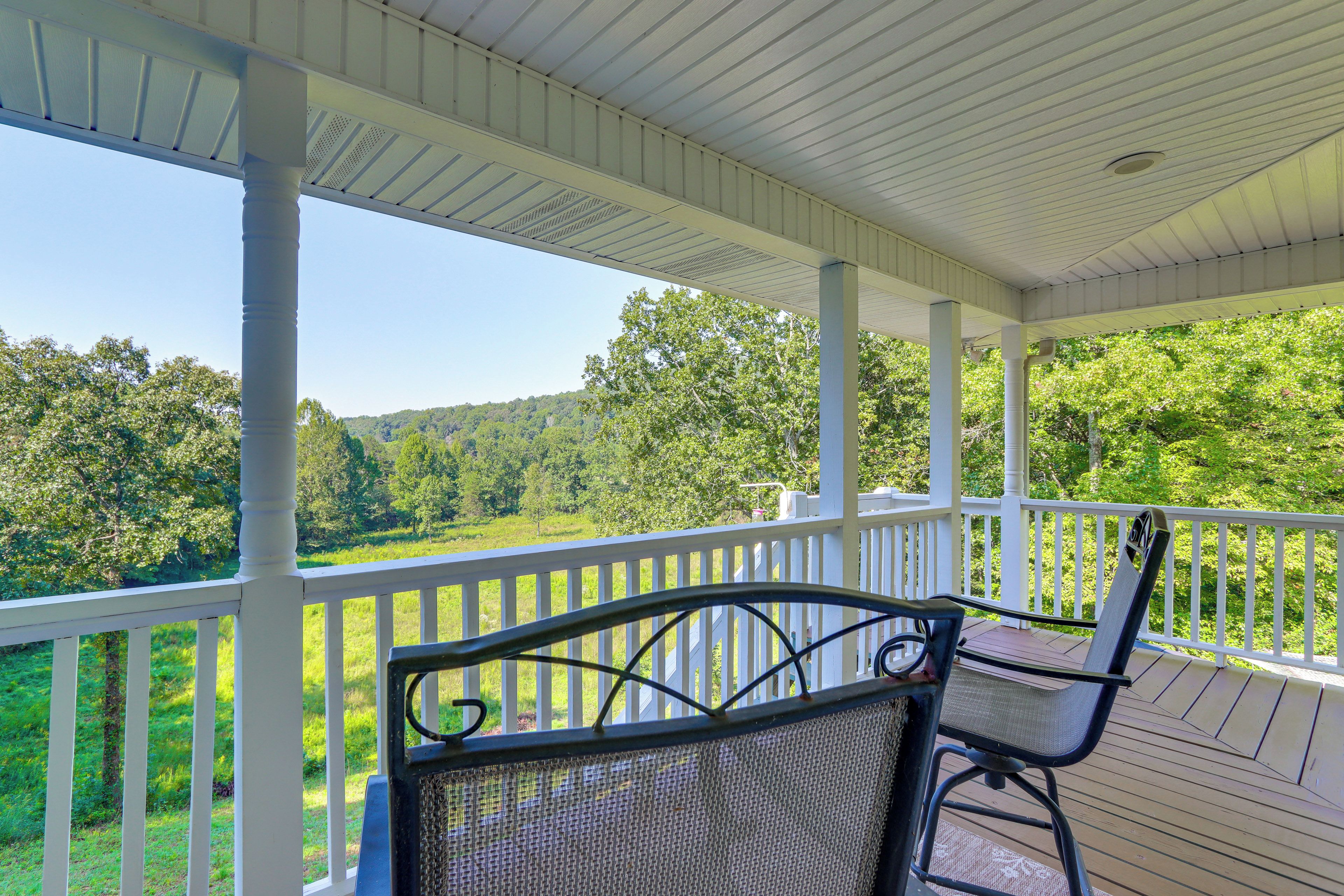 A covered outdoor area with a view of a green landscape.