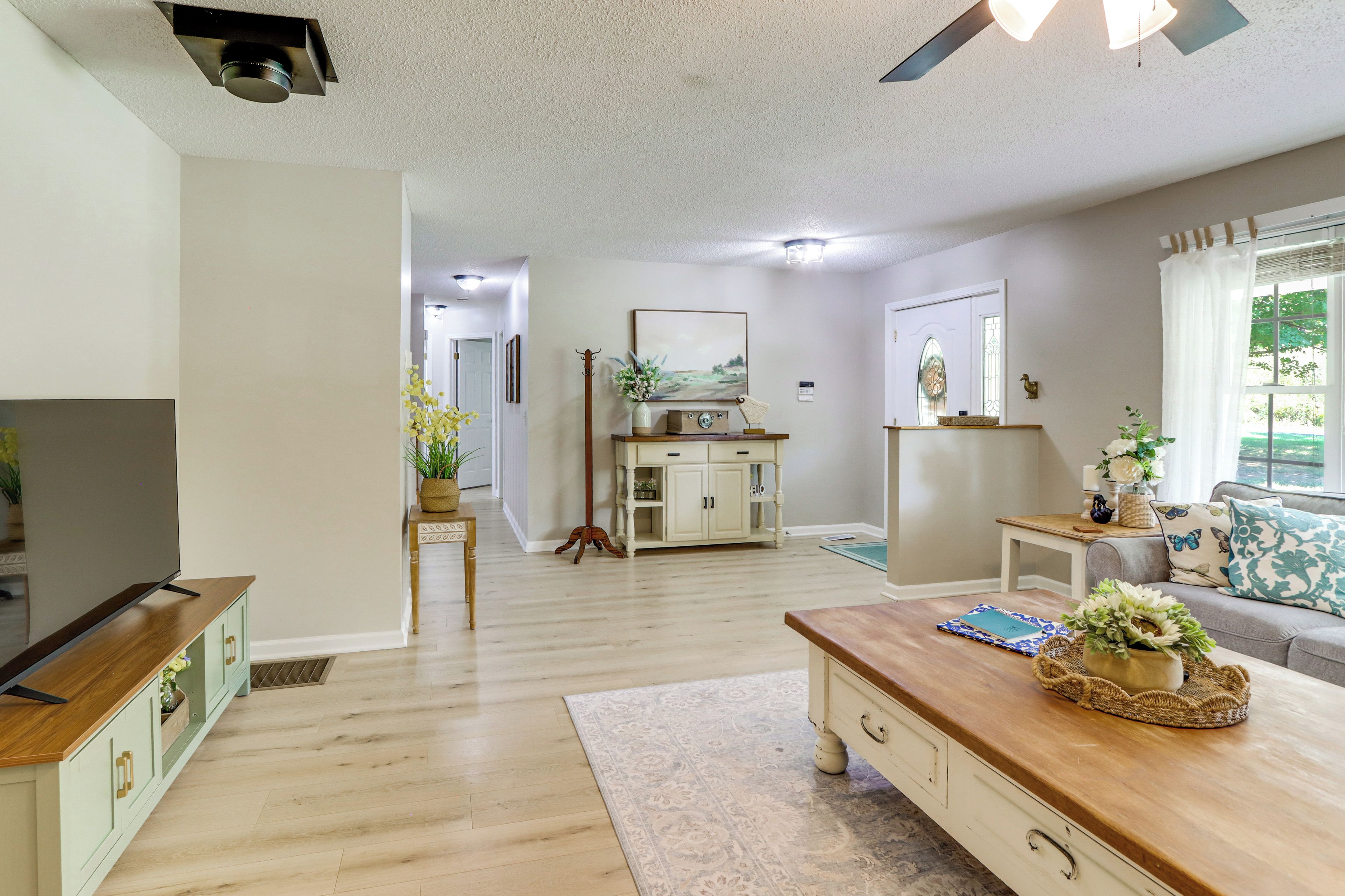 A spacious living room with a television, wooden coffee table, and a sofa.