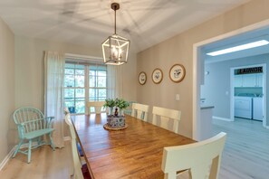 Una sala da pranzo con un tavolo di legno, sedie, un lampadario e piatti decorativi appesi al muro.