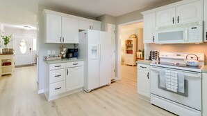 Eine moderne Küche mit weißen Schränken, einem Kühlschrank, einer Mikrowelle und einem Backofen.