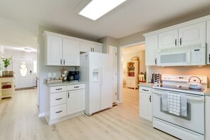 Una cucina moderna con mobili bianchi, un frigorifero, un forno a microonde e un forno.