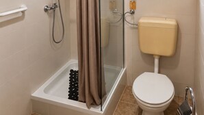 A bathroom with a glass-enclosed shower, a toilet, and a window with a plant. - Eco Beach House Corrine - 100 m from the Beach (Peroj)
