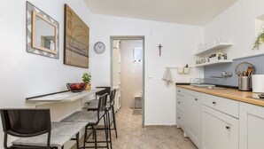 A modern kitchen with white cabinets, a wooden countertop, and a dining area with a bench and chairs. - Eco Beach House Corrine - 100 m from the Beach (Peroj)