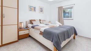 A bedroom with a bed, nightstand, wardrobe, and a window with curtains. - Eco Beach House Corrine - 100 m from the Beach (Peroj)