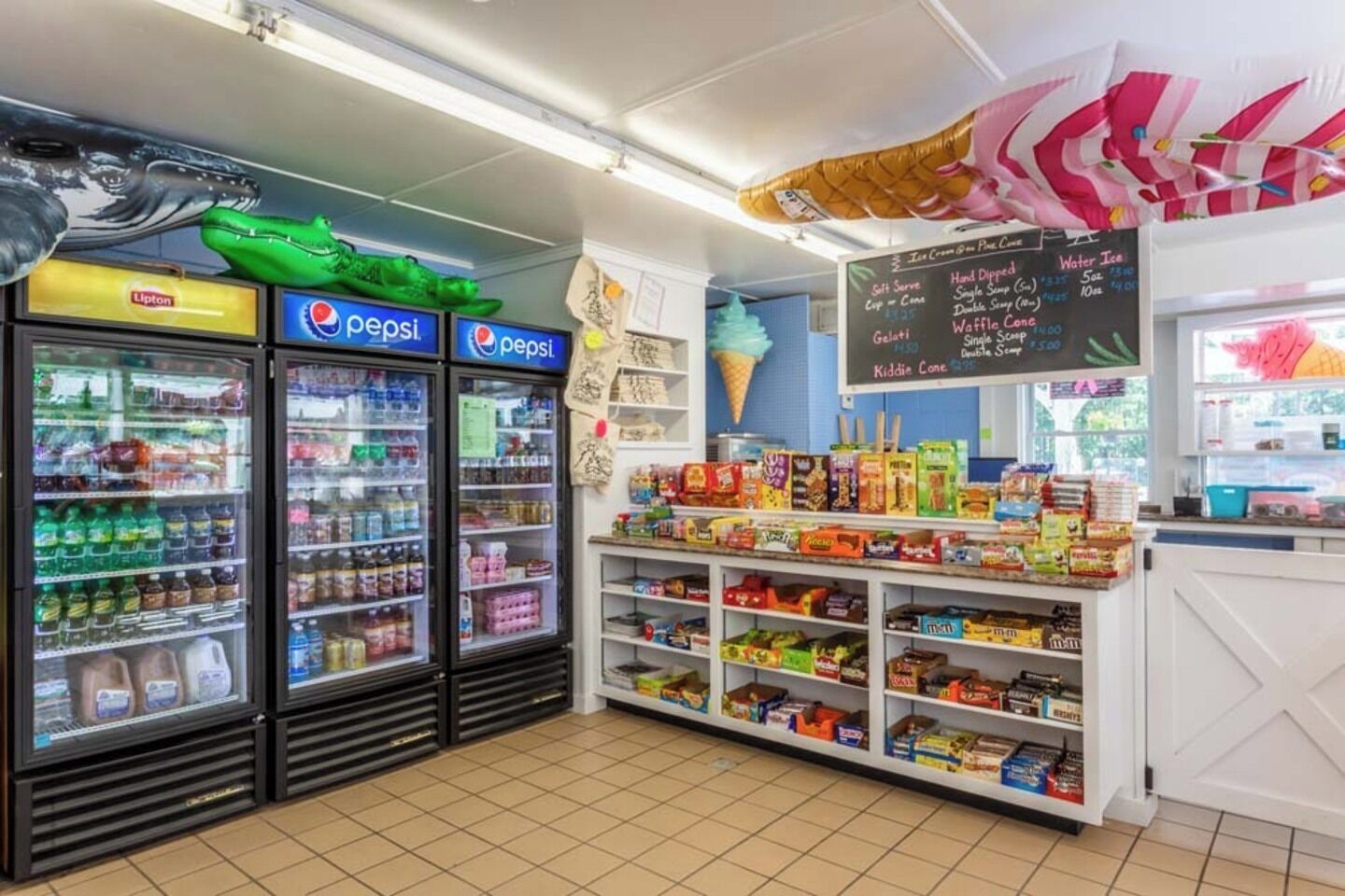 Une épicerie de quartier avec des réfrigérateurs remplis de Pepsi, une variété de collations et un tableau noir servant de menu.