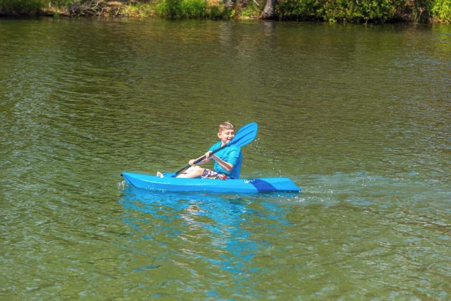 A person in a blue kayak on a calm body of water.