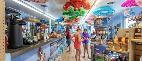 Una tienda luminosa con varios productos en estantes y adornos colgantes, incluyendo un cangrejo de gran tamaño y un personaje de un programa infantil.