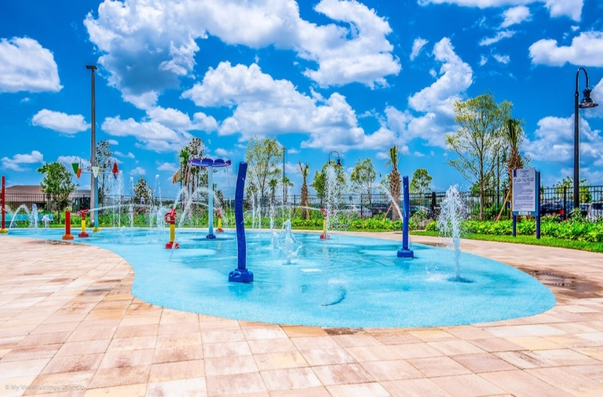 A water park with multiple fountains and a tiled walkway.