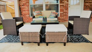 An outdoor seating area with wicker furniture, cushions, and a table.