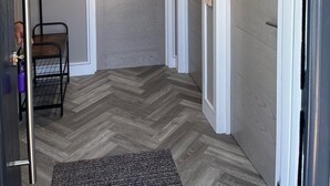 A hallway with a herringbone-patterned floor, a metal rack, and a door with a textured finish. - Secure, Detached bungalow overlooking Weston-super-Mare, the Severn and Wales (Hutton)