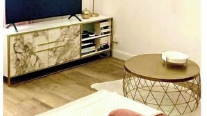 A living room with a TV on a marble cabinet, a round coffee table, and a pink sofa. - Le Fuselier - Hyper Centre Cathédrale (Reims)