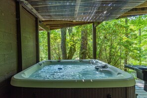 A hot tub under a wooden pergola with a view of a forested area. - 2 mins to Ski! Hot Tub+Fire Pit, Fireplace, Grill! (Mars Hill)