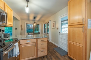 A kitchen with wooden cabinets, a granite countertop, a built-in oven, and a hanging light fixture. - 2 mins to Ski! Hot Tub+Fire Pit, Fireplace, Grill! (Mars Hill)