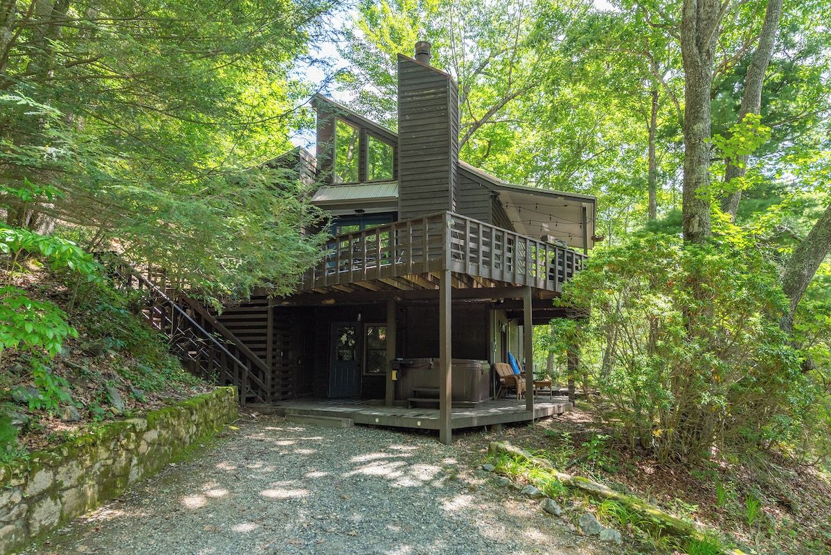 Une cabane dotée d’une terrasse en bois, d’un bain à remous et d’un escalier menant à un niveau supérieur.