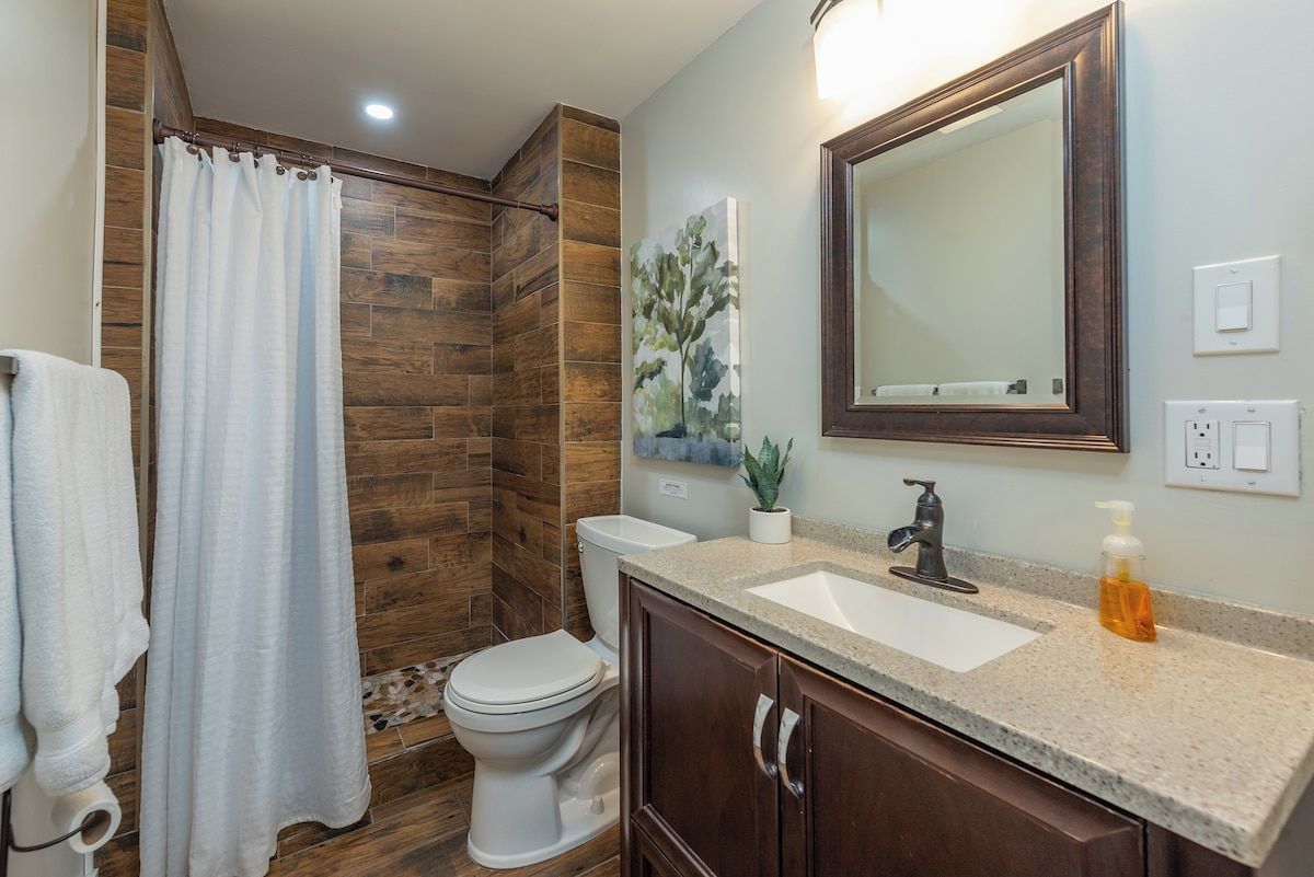 Un baño con ducha, inodoro, lavabo y espejo.