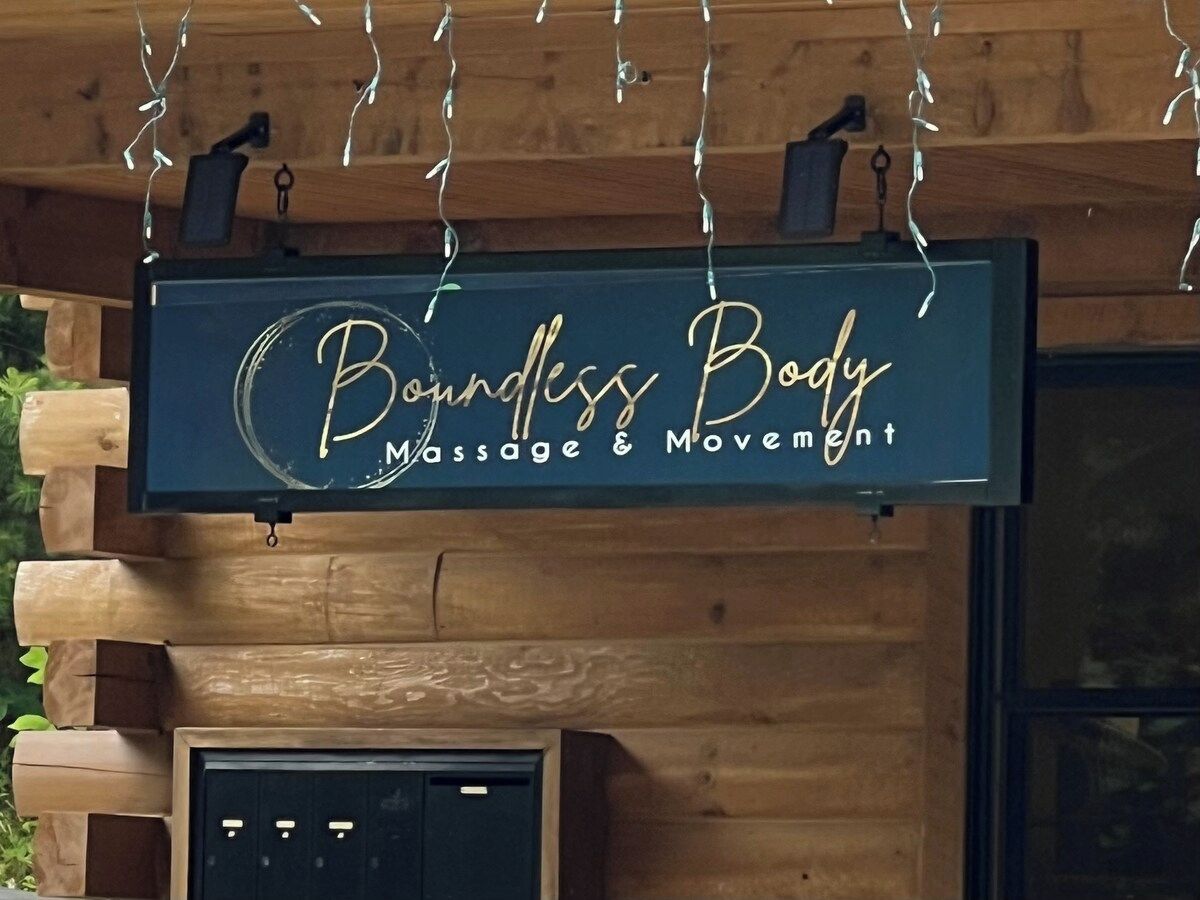 Une enseigne indiquant « Bounless Body Massage & Movement » est accrochée à un mur en bois.
