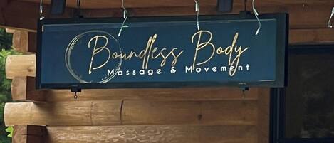 Une enseigne indiquant « Bounless Body Massage & Movement » est accrochée à un mur en bois.