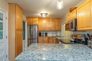 A kitchen with wooden cabinets, stainless steel appliances, and granite countertops.
