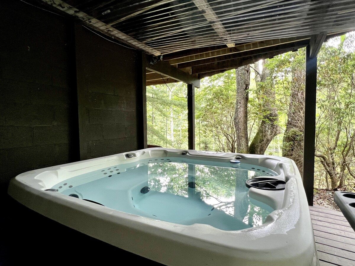 A hot tub in a covered outdoor area with a view of trees.