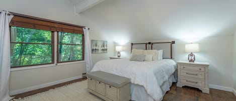 A bedroom with a bed, bedside tables, a bench, and a ceiling fan.