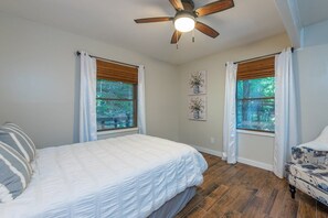 A bedroom with a bed, two windows with curtains, a ceiling fan, and a wooden floor. - 2 mins to Ski! Hot Tub+Fire Pit, Fireplace, Grill! (Mars Hill)