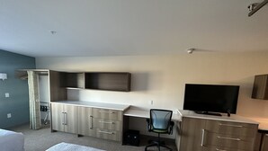 A hotel room with a bed, a desk with a chair, a television, and a wardrobe. - Home2 Suites By Hilton Racine (Sturtevant)