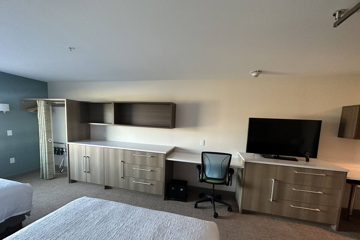 A hotel room with a bed, a desk with a chair, a television, and a wardrobe.