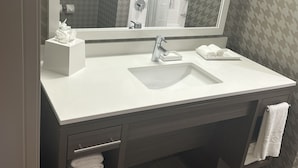 A modern bathroom with a white sink, a large mirror, and a towel rack. - Home2 Suites By Hilton Racine (Sturtevant)