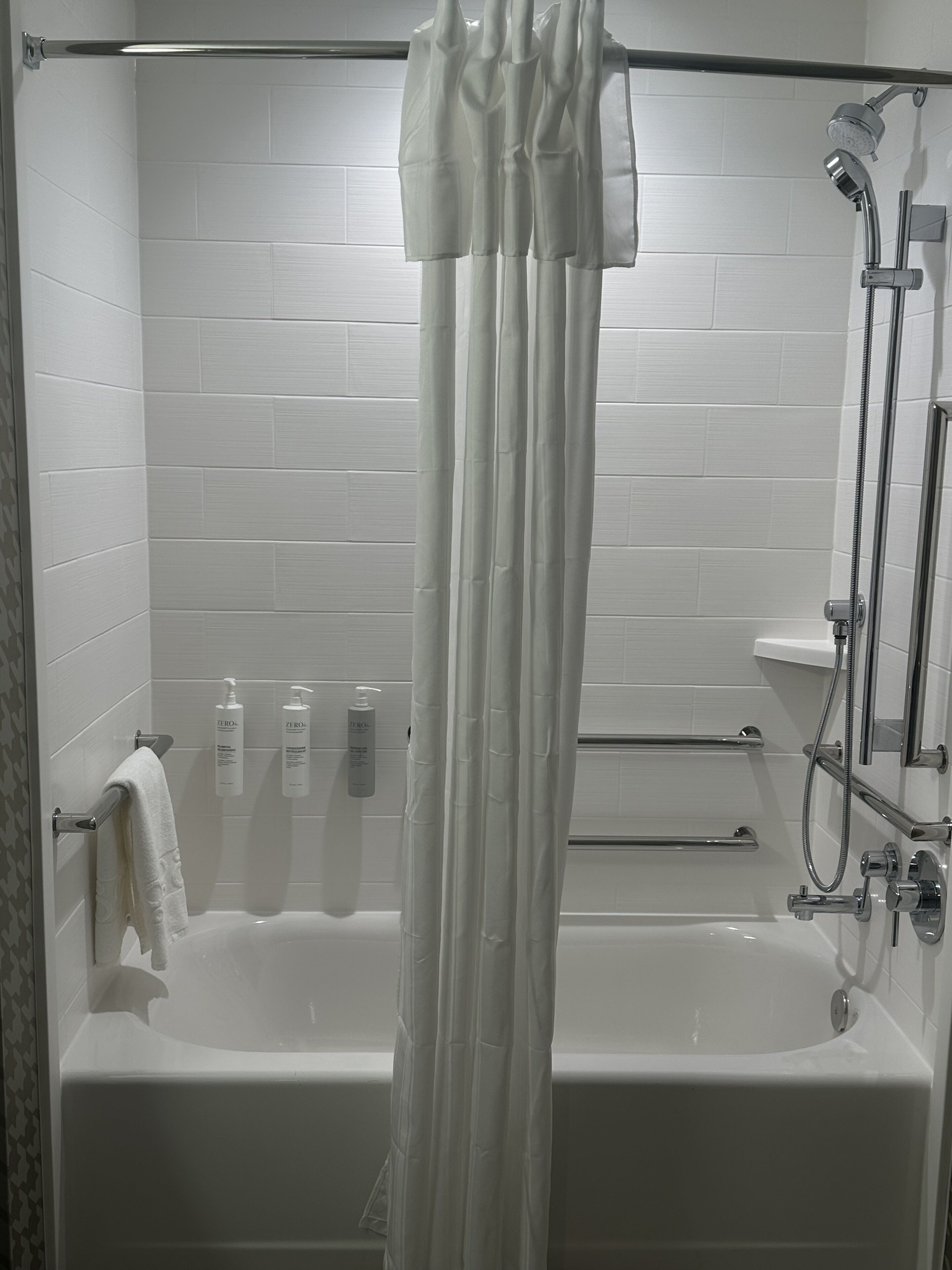 A modern bathroom with a bathtub, shower, and white tiled walls.