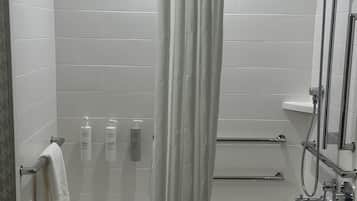 A modern bathroom with a bathtub, shower, and white tiled walls.
