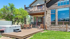 A two-story house with a deck, outdoor seating, and a hot tub.