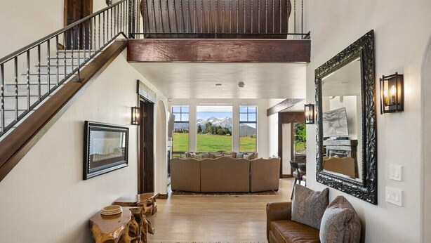 A spacious living area with a staircase, a large mirror, and a view of the outdoors.