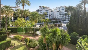 A residential area with white apartment buildings, palm trees, and well-maintained gardens.