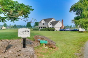 Situated in a serene grassy area, this traditional house offers a charming retreat with a prominent chimney and a gabled roof.